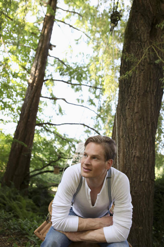 西方人,一个人,坐,笑,微笑,露齿笑,竖图,室外,白天,正面,植物,欧洲,欧洲人,仅一个男性,仅一个人,仅一个中年男性,弯腰,阴影,服装,光线,影子,扭头,注视,休闲装,树,树木,衣服,绿色,阳光,自然,观察,看,转头,休闲,休闲服,搭,服饰,生长,成长,观看,察看,搭着,关注,弯身,男人,男性,中年男性,白种人,坐着,半身,彩图