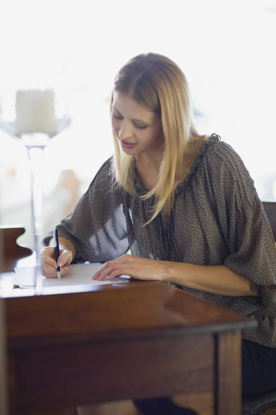 西方人,一个人,坐,笑,微笑,竖图,室内,白天,正面,窗户,桌面,桌子,照明,欧洲,欧洲人,仅一个年轻女性,仅一个女性,仅一个人,握,写字,服装,传递,信息,木制,笔,邮件,灯光,办公用品,联系,拿,拿着,注视,休闲装,书桌,水笔,玻璃窗,灯,文具,衣服,灰色,课桌,木制品,学习用品,灯具,落地灯,观察,看,休闲,休闲服,金色,联络,握着,邮递,通信,服饰,信件,观看,文具用品,照亮,察看,书写,照明设备,关注,邮政,一封,年轻女性,女人,女性,白种人,长发,坐着,半身,彩图