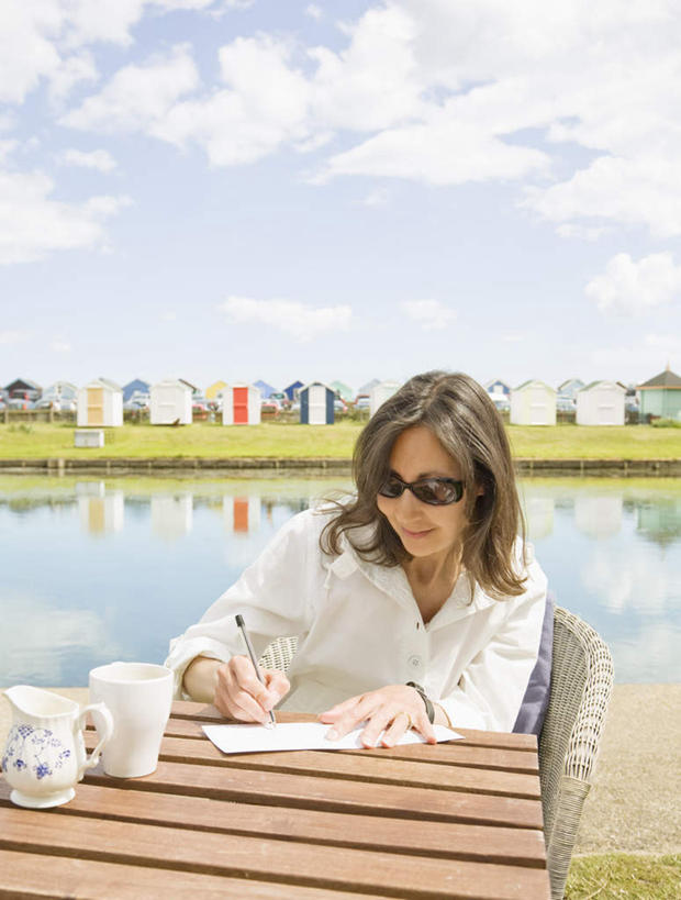 西方人,一个人,坐,笑,微笑,露齿笑,竖图,室外,白天,正面,草地,草坪,湖,湖泊,水,植物,桌面,桌子,杯子,椅子,欧洲,欧洲人,仅一个女性,仅一个人,握,写字,阴影,服装,传递,光线,信息,木制,笔,墨镜,眼镜,影子,邮件,陶瓷,木椅,湖面,水流,水面,云,云朵,办公用品,陶瓷制品,联系,拿,云彩,拿着,注视,休闲装,文具,草,衣服,蓝色,绿色,白云,倒影,蓝天,天空,阳光,马克杯,木制品,水杯,太阳镜,太阳眼镜,学习用品,湖水,天,观察,看,仅一个中年女性,休闲,休闲服,遮阳镜,联络,握着,邮递,通信,服饰,晴朗,信件,观看,文具用品,察看,倒映,书写,关注,邮政,反照,女人,女性,中年女性,白种人,晴空,坐着,半身,彩图