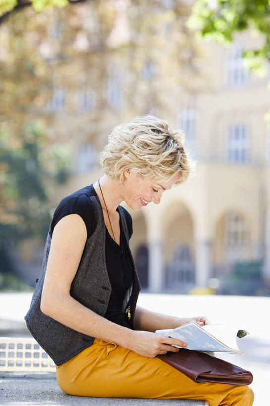 西方人,一个人,商务人士,商务女性,坐,捧,笑,微笑,竖图,室外,白天,侧面,植物,道路,路,公路,书籍,椅子,欧洲,欧洲人,仅一个女性,仅一个人,一本,阴影,套装,朦胧,模糊,光线,影子,长椅,交通,注视,树,树木,绿色,黑色,阳光,自然,观察,看,仅一个中年女性,金色,生长,成长,观看,察看,关注,商务装,工薪阶层,排椅,女人,女性,中年女性,白种人,卷发,白领,上班族,书,图书,马路,端,端着,捧着,手捧,坐着,半身,彩图,短发