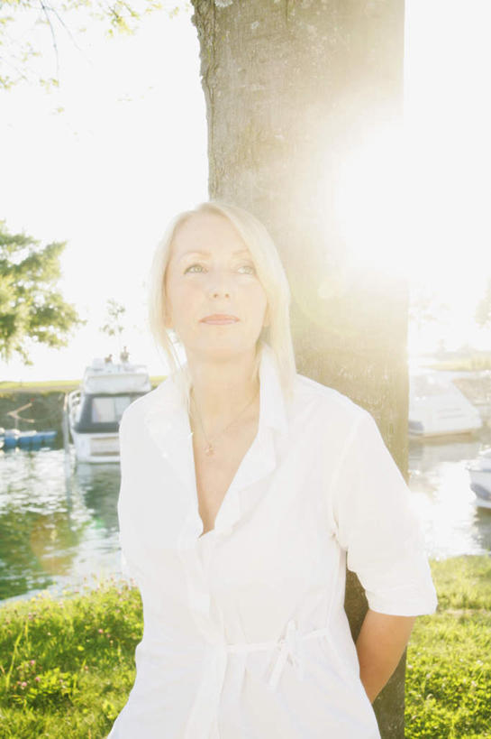 西方人,一个人,站,笑,微笑,竖图,室外,白天,正面,草地,草坪,植物,欧洲,欧洲人,仅一个女性,仅一个人,阴影,服装,朦胧,模糊,光线,影子,树桩,注视,休闲装,草,树,树干,树木,衣服,绿色,白色,阳光,自然,观察,看,靠,靠着,站着,仅一个中年女性,休闲,休闲服,木桩,服饰,生长,成长,观看,察看,关注,女人,女性,中年女性,白种人,站立,半身,彩图