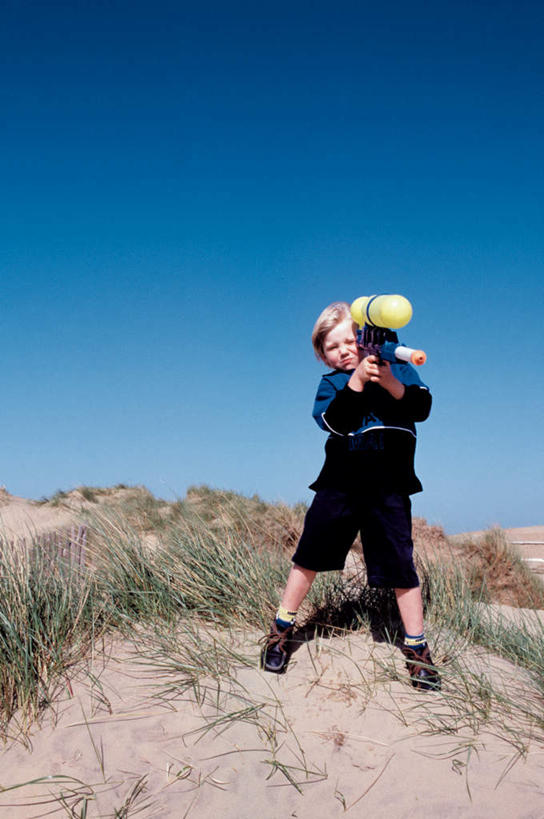 西方人,儿童,一个人,站,笑,微笑,竖图,室外,白天,正面,游戏,纯洁,竞争,草地,沙滩,植物,玩具,欧洲,欧洲人,仅一个男性,仅一个人,对抗,握,阴影,服装,冲突,光线,枪支,沙子,影子,海岸,沙地,拿,玩,拿着,注视,休闲装,破坏,娱乐,草,小孩,衣服,蓝色,绿色,蓝天,天空,阳光,天,观察,看,站着,仅一个小孩,休闲,休闲服,武器,可爱,童年,童趣,益智,战争,握着,服饰,手枪,晴朗,观看,张开双腿,活动,损坏,察看,攻击,威胁,对立,发泄,关注,矛盾,消遣,智力,兵器,防御,枪械,童真,烂漫,无邪,万里无云,弹夹,敌对,挫败,斗争,抗拒,抗衡,宣泄,杀伤,威慑,展开双腿,子弹夹,天真,危险,男孩,男人,男性,白种人,孩子,海滩,晴空,晴空万里,玩耍,嬉戏,站立,彩图,全身,男生,伸展双腿