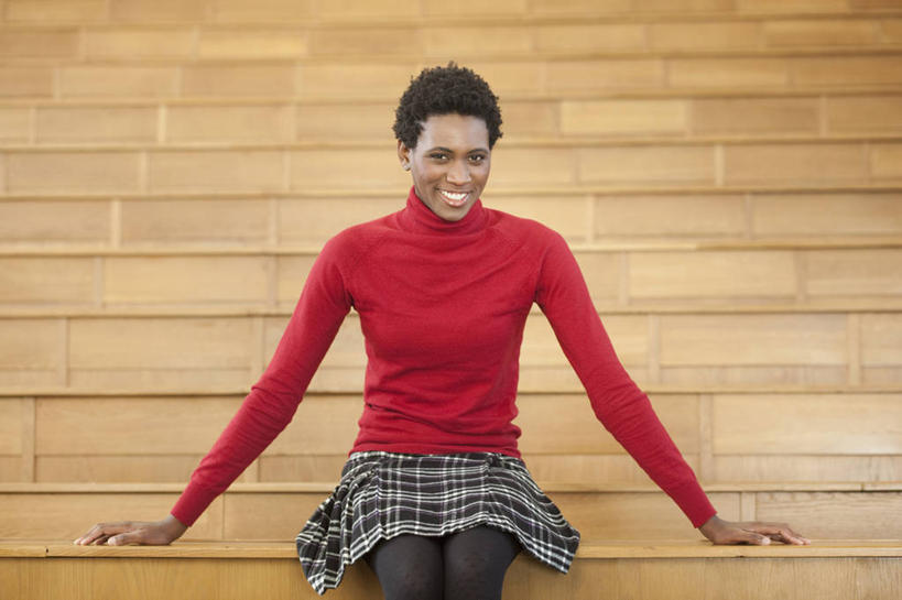 西方人,一个人,学校,教学楼,坐,笑,微笑,露齿笑,横图,室内,白天,正面,毛衣,桌子,欧洲,非洲,黑人,欧洲人,仅一个年轻女性,仅一个女性,仅一个人,木制,墙,注视,书桌,校园,墙壁,墙面,红色,课桌,木制品,观察,看,教室,搭,观看,察看,搭着,关注,线衫,毛线衣,绒线衣,年轻女性,女人,女性,非洲人,坐着,半身,彩图,绒衣,套衫,套头毛衣,线衣,教学大楼,报告厅