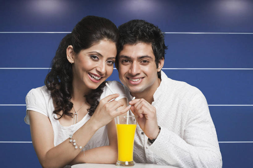 果汁,两个人,坐,笑,微笑,露齿笑,横图,室内,白天,正面,民族服装,爱情,餐桌,桌子,杯子,椅子,亚洲,握,服装,塑料,橙汁,饮品,浪漫,拿,拿着,注视,休闲装,玻璃制品,饮料,衣服,黄色,水杯,塑料制品,吸管,观察,看,休闲,温暖,温馨,休闲服,恩爱,握着,恋人,服饰,餐台,观看,和睦,察看,空心,甜橙,关注,可口,饮管,适口,男人,男性,年轻男性,年轻女性,女人,女性,亚洲人,印度人,情侣,玻璃杯,橙子,橙,坐着,半身,彩图,传统服装,民俗服,鹄壳,黄橙,黄果,金橙,金环,金球,糖橙,伴侣,融洽,圆柱状