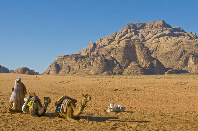 一个人,站,横图,室外,白天,仰视,民族服装,旅游,度假,石头,美景,沙漠,山,山脉,野生动物,约旦,亚洲,仅一个男性,仅一个人,阴影,光线,石子,影子,景观,山峰,山峦,娱乐,骆驼,蓝色,蓝天,天空,阳光,自然,动物,群山,天,趴着,站着,仅一个老年男性,两只,享受,休闲,景色,放松,运输,自然风光,西亚,沙漠之舟,双峰骆驼,约旦哈希姆王国,瓦迪拉姆,瓦迪拉姆保护区,老年男性,男人,男性,阿拉伯人,白种人,亚洲人,大漠,砂漠,石块,岩石,趴,站立,彩图,低角度拍摄,全身,传统服装,民俗服