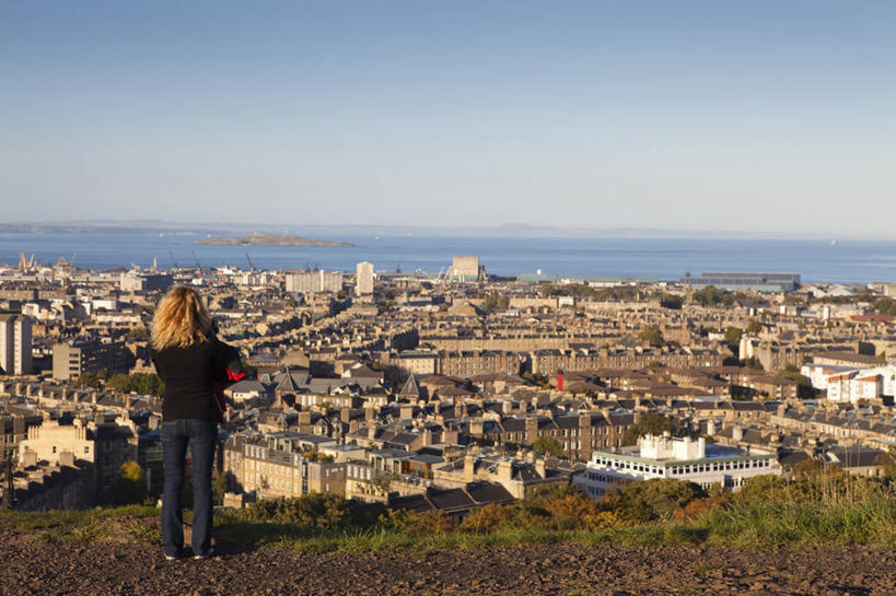 一个人,家,站,横图,室外,白天,度假,草地,草坪,海浪,海洋,石头,美景,山,山脉,植物,窗户,城市风光,城市,英国,欧洲,仅一个女性,仅一个人,一排,许多,阴影,波纹,服装,整齐,光线,石子,影子,房屋,墙,屋顶,屋子,景观,浪花,山峰,涟漪,山峦,首都,很多,顶棚,注视,休闲装,娱乐,楼房,苏格兰,玻璃窗,墙壁,墙面,住宅,草,排列,背面,衣服,蓝色,绿色,倒影,蓝天,水纹,天空,阳光,海水,波浪,群山,天,观察,看,站着,仅一个中年女性,享受,休闲,休闲服,景色,放松,服饰,晴朗,观看,察看,倒映,西欧,队列,关注,大不列颠,海景,大不列颠及北爱尔兰联合王国,万里无云,首府,水晕,大不列颠联合王国,日不落英帝国,苏格兰王国,反照,爱丁堡,卡尔顿山,女人,女性,中年女性,大海,风浪,海,海水的波动,近岸浪,石块,岩石,涌浪,晴空,晴空万里,站立,彩图,全身,房子
